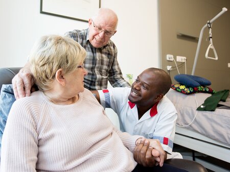  Zorgkundige biedt emotionele steun door de hand vast te houden van een patiënt en haar echtgenoot.